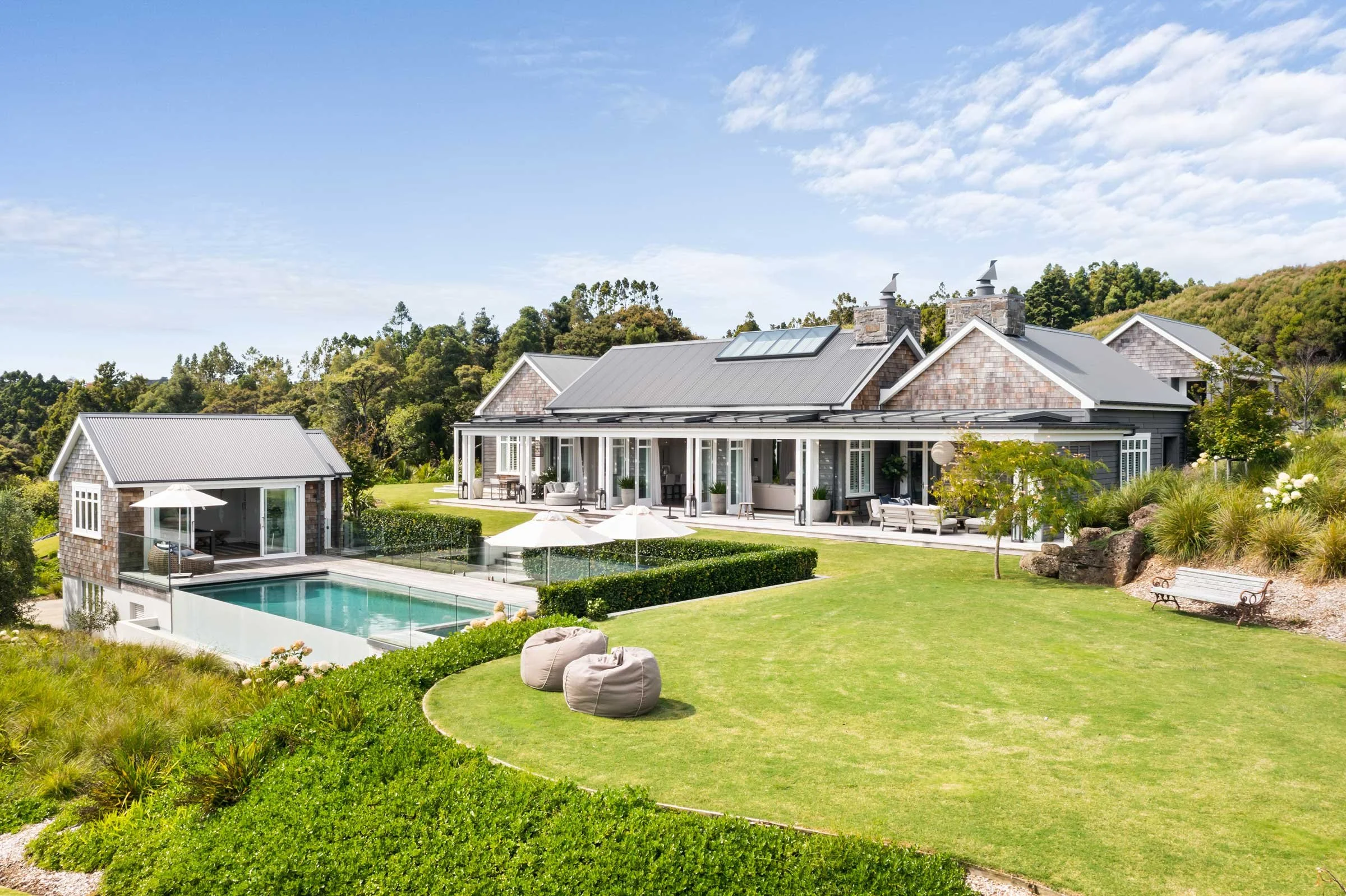 The Main House at Bluestone Estate from the lawn: the infinity pool, the pool house, beanbags, and the verandah.